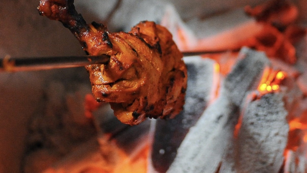 Tandoori chicken grilling over open coals in the clay tandoor at The Imperial Tandoor, Peterborough